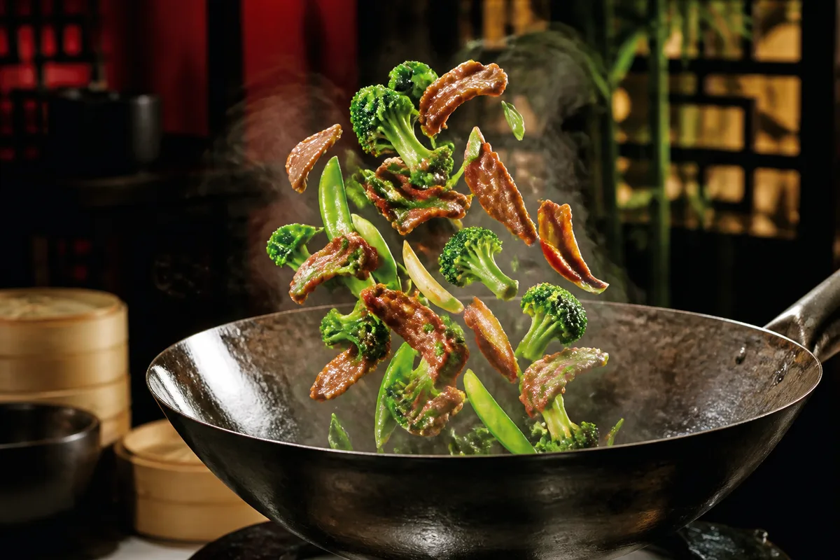 Légumes et lamelles de viande sautés en mouvement dans un wok fumant